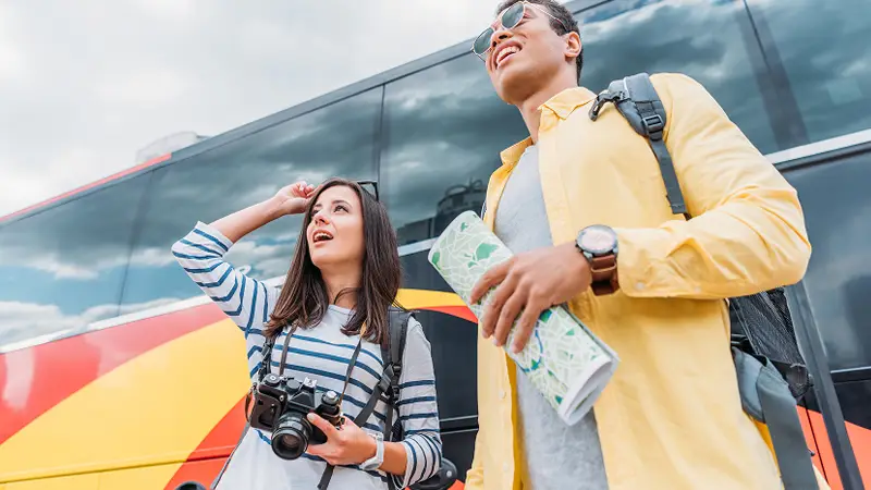 Tourists standing by a bus, looking at their destination